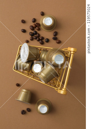 Golden coffee capsules in shopping tray, coffee beans on beige background, top view Golden coffee capsules in shopping tray, coffee beans on beige background, top view 119575024
