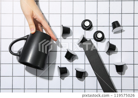Black coffee capsules, box and cup in hand on light background, top view 119575026