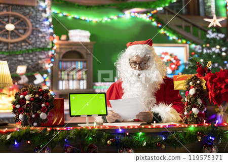 Santa Claus checking his naughty or nice list next to isolated mockup, preparing for his journey around the world to bring gifts on Christmas eve. Old man making children happy on x mas. Santa Claus checking his naughty or nice list next to isolated mockup, preparing for his journey around the world to bring gifts on Christmas eve. Old man making children happy on x mas. 119575371