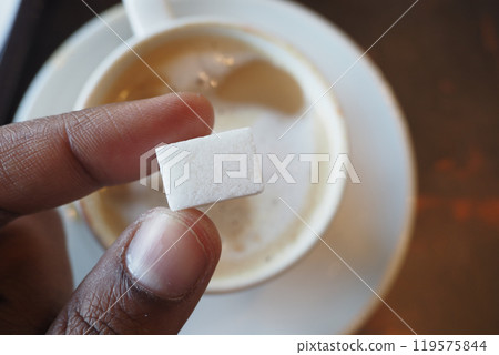 A Sugar Cube Delicately Being Added to a Warm Cup of Coffee, Enhancing the Experience 119575844