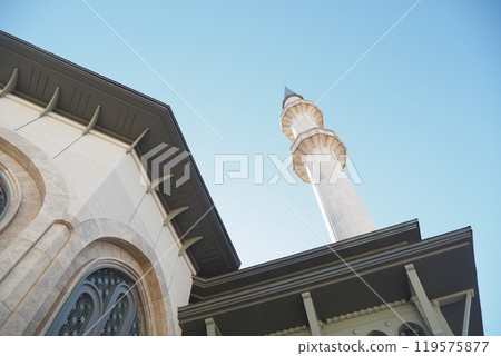 A beautiful mosque featuring a stunning minaret prominently showcased against a clear blue sky 119575877