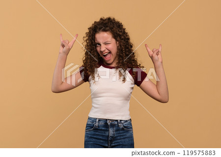 Young girl flashing rock hand signs with enthusiastic expression Young girl flashing rock hand signs with enthusiastic expression 119575883