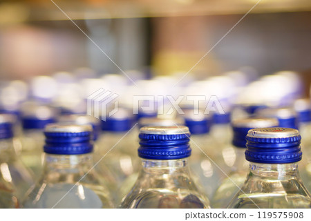 A neatly organized shelving display featuring stacked water bottles, all equipped with blue caps A neatly organized shelving display featuring stacked water bottles, all equipped with blue caps 119575908