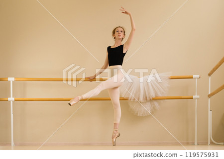 Ballet dancer gracefully extending arm while balancing on pointe 119575931