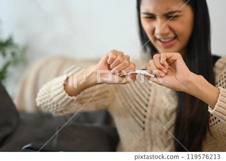 Frustrated woman destroying her credit card. Financial management and debt reduction concept 119576213