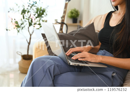 Cropped shot young woman working from home, typing on laptop keyboard Cropped shot young woman working from home, typing on laptop keyboard 119576232