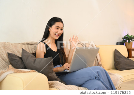 Cheerful young woman enjoying a video call from comfort of her home 119576235