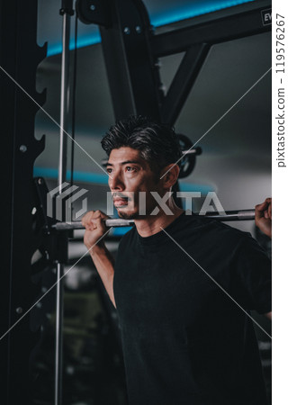 A man in his 40s working out his lower body at the gym A man in his 40s working out his lower body at the gym 119576267