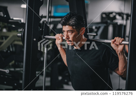 A man in his 40s working out his lower body at the gym A man in his 40s working out his lower body at the gym 119576276