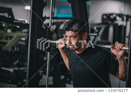 A man in his 40s working out his lower body at the gym A man in his 40s working out his lower body at the gym 119576277