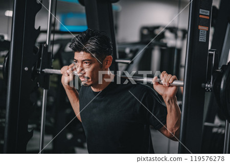 A man in his 40s working out his lower body at the gym A man in his 40s working out his lower body at the gym 119576278