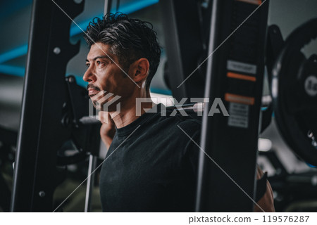 A man in his 40s working out his lower body at the gym 119576287
