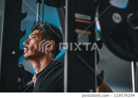 A man in his 40s working out his lower body at the gym 119576294