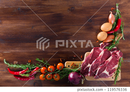 Raw beef with fresh vegetables on wooden background Raw beef with fresh vegetables on wooden background 119576336