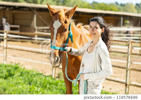 Armenian girl, owner of horse, walks pet outdoor in paddock Armenian girl, owner of horse, walks pet outdoor in paddock 119576686