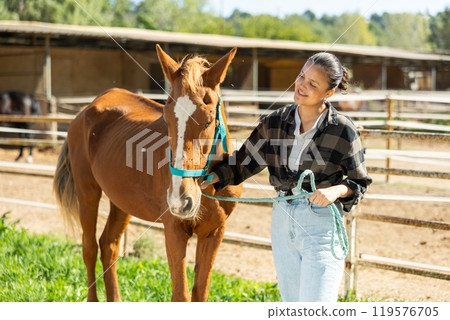 Young woman with horse in horse paddock 119576705