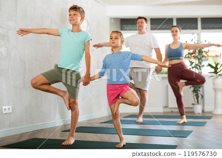 Sweet sister and brother practicing tree pose of yoga in pair 119576730