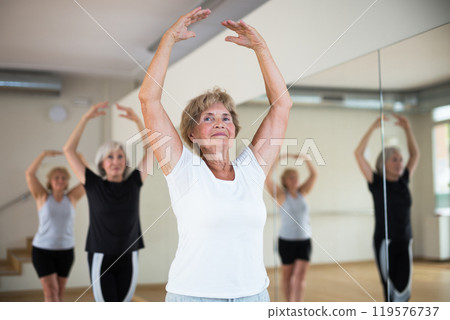 Senior women in sportswear dancing ballet inside gym Senior women in sportswear dancing ballet inside gym 119576737