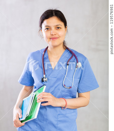 Smiling female medical student holding workbooks with lecture notes 119576981