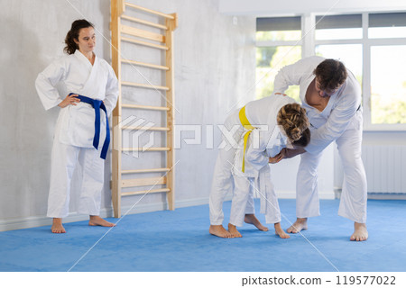 Parent with child athletes in pair conduct training battle in oriental fighting technique Parent with child athletes in pair conduct training battle in oriental fighting technique 119577022