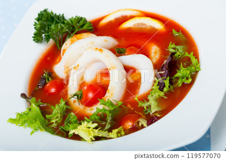 Spicy tomato soup with squids and greens in a white bowl Spicy tomato soup with squids and greens in a white bowl 119577070