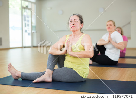 Active elderly woman practicing yoga at group 119577071