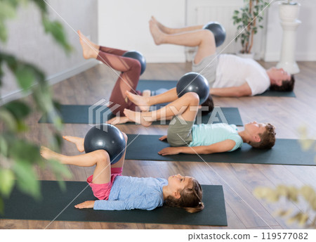 Family with two kids doing pilates with softball 119577082
