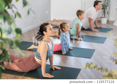 Mom, dad, son and daughter perform pose dog muzzle up - cobra, Urdhva Mukha Shvanasana- Bhujangasana Mom, dad, son and daughter perform pose dog muzzle up - cobra, Urdhva Mukha Shvanasana- Bhujangasana 119577128