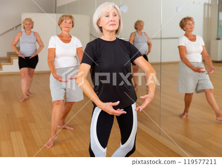 Senior women in sportswear dancing ballet inside gym 119577211