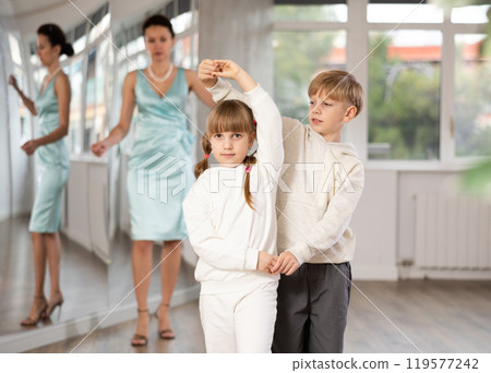 Tween girl and boy practicing waltz in dance hall with female mentor Tween girl and boy practicing waltz in dance hall with female mentor 119577242