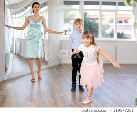 Girl rehearsing elegant curtsy with boy dance partner and female teacher Girl rehearsing elegant curtsy with boy dance partner and female teacher 119577261