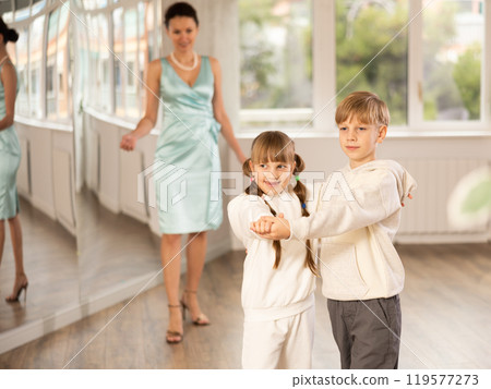 Tween boy and girl performing waltz in pair in dance hall Tween boy and girl performing waltz in pair in dance hall 119577273