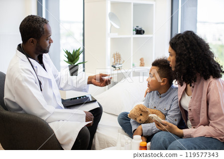 African male doctor taking temperature of young boy with parent present African male doctor taking temperature of young boy with parent present 119577343