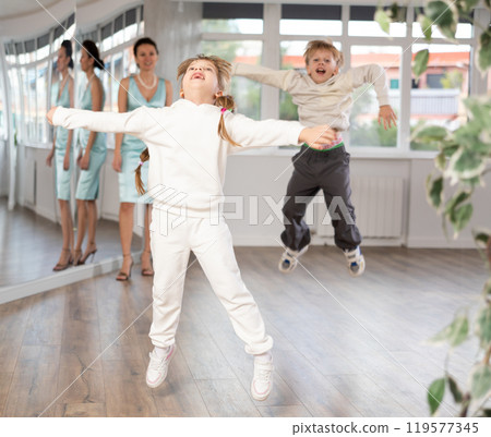 Cheerful girl jumping during dance lesson in choreography studio Cheerful girl jumping during dance lesson in choreography studio 119577345