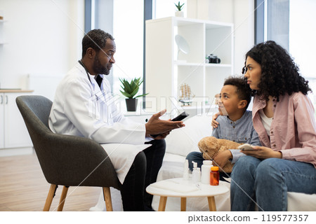 Doctor consulting boy and mother in medical office 119577357