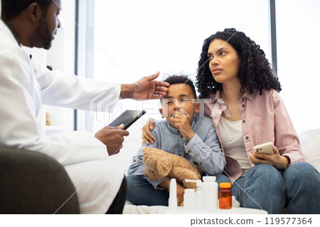 Concerned mother with sick child visiting male doctor in clinic 119577364