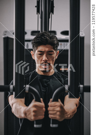 A man in his 40s working out his upper body at the gym 119577428
