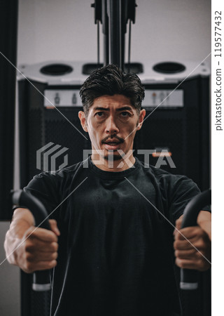 A man in his 40s working out his upper body at the gym A man in his 40s working out his upper body at the gym 119577432