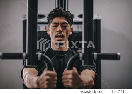 A man in his 40s working out his upper body at the gym A man in his 40s working out his upper body at the gym 119577433
