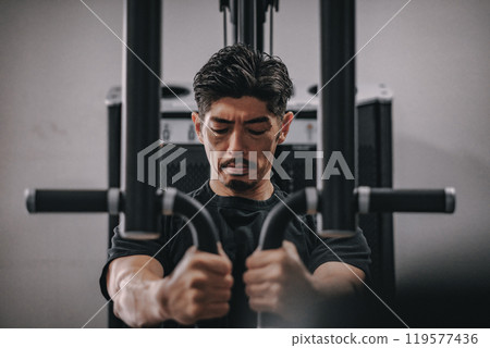 A man in his 40s working out his upper body at the gym 119577436