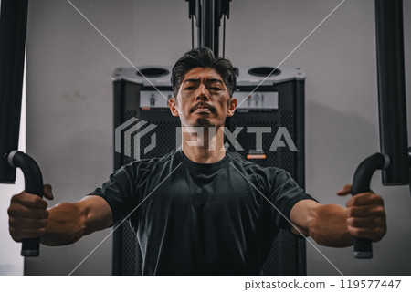 A man in his 40s working out his upper body at the gym 119577447