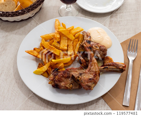 Baked lamb ribs with french fries and aioli sauce 119577481