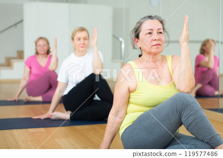 Active elderly woman practicing yoga at group Active elderly woman practicing yoga at group 119577486