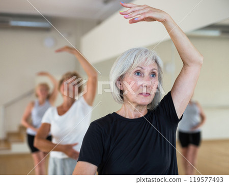 Portrait of a mature woman, standing on the 4th position of the ballet stand in a dance studio 119577493
