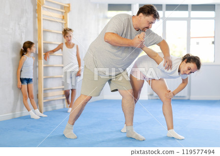 Self-defense lesson for the family - mom and dad practice doing painful power grip. Children are watching 119577494