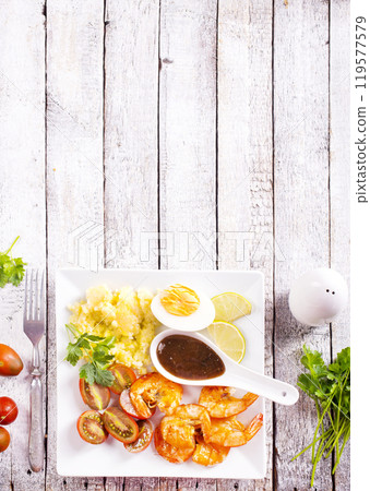 Grilled shrimps with greens and corn porridge Grilled shrimps with greens and corn porridge 119577579