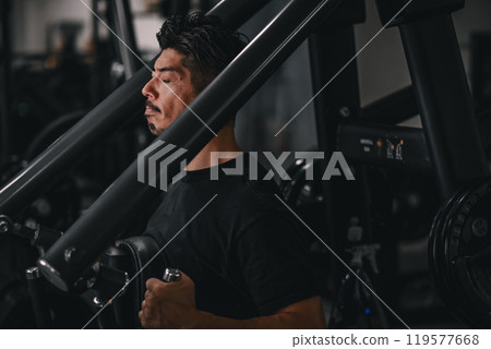A man using a machine to train his upper body at the gym A man using a machine to train his upper body at the gym 119577668