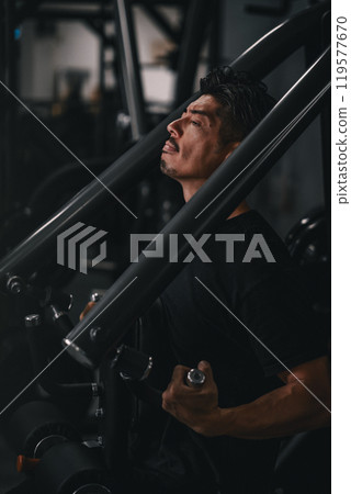 A man using a machine to train his upper body at the gym A man using a machine to train his upper body at the gym 119577670