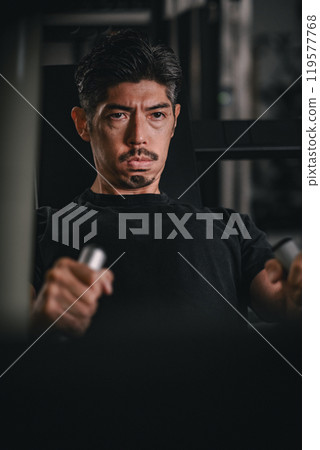 Close-up of a man using machines to train his upper body at the gym 119577768
