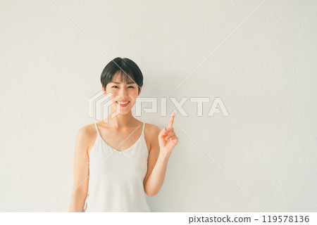 一位身穿吊帶背心的年輕女子在白色背景前伸出食指 119578136